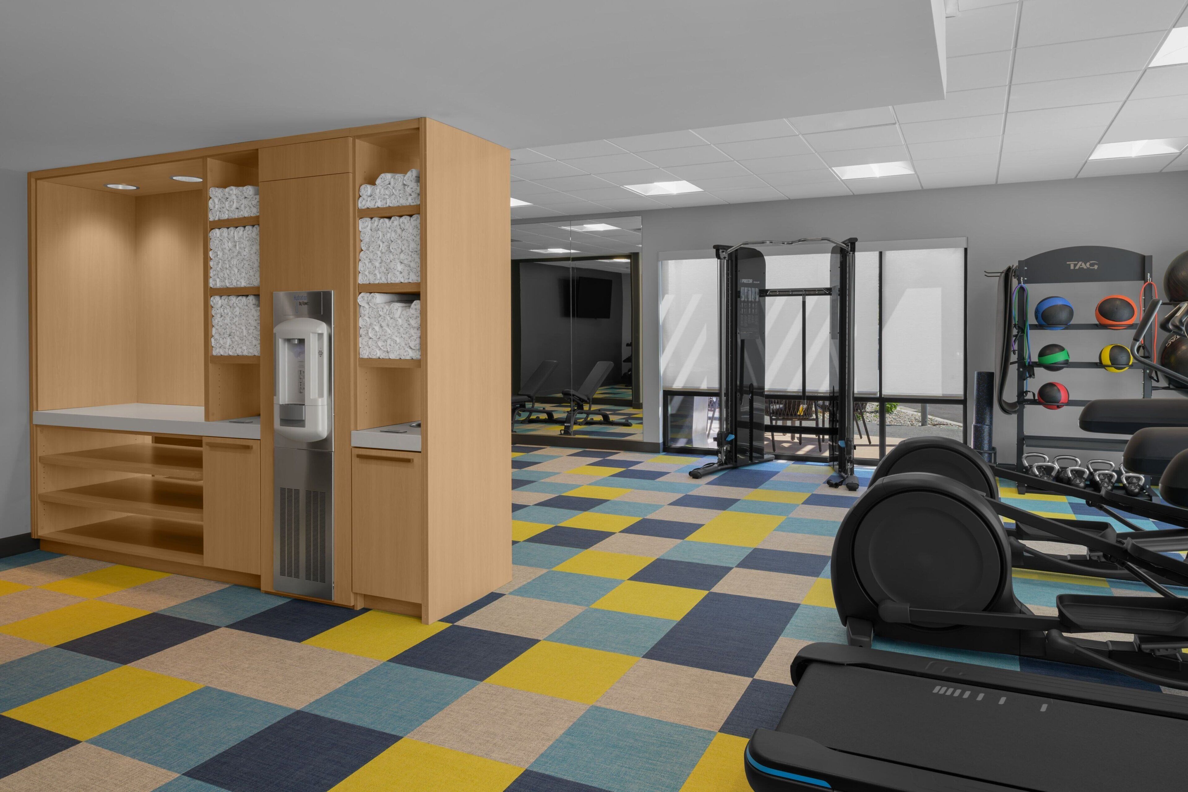 A gym with a checkered floor, weightlifting equipment, and a treadmill.