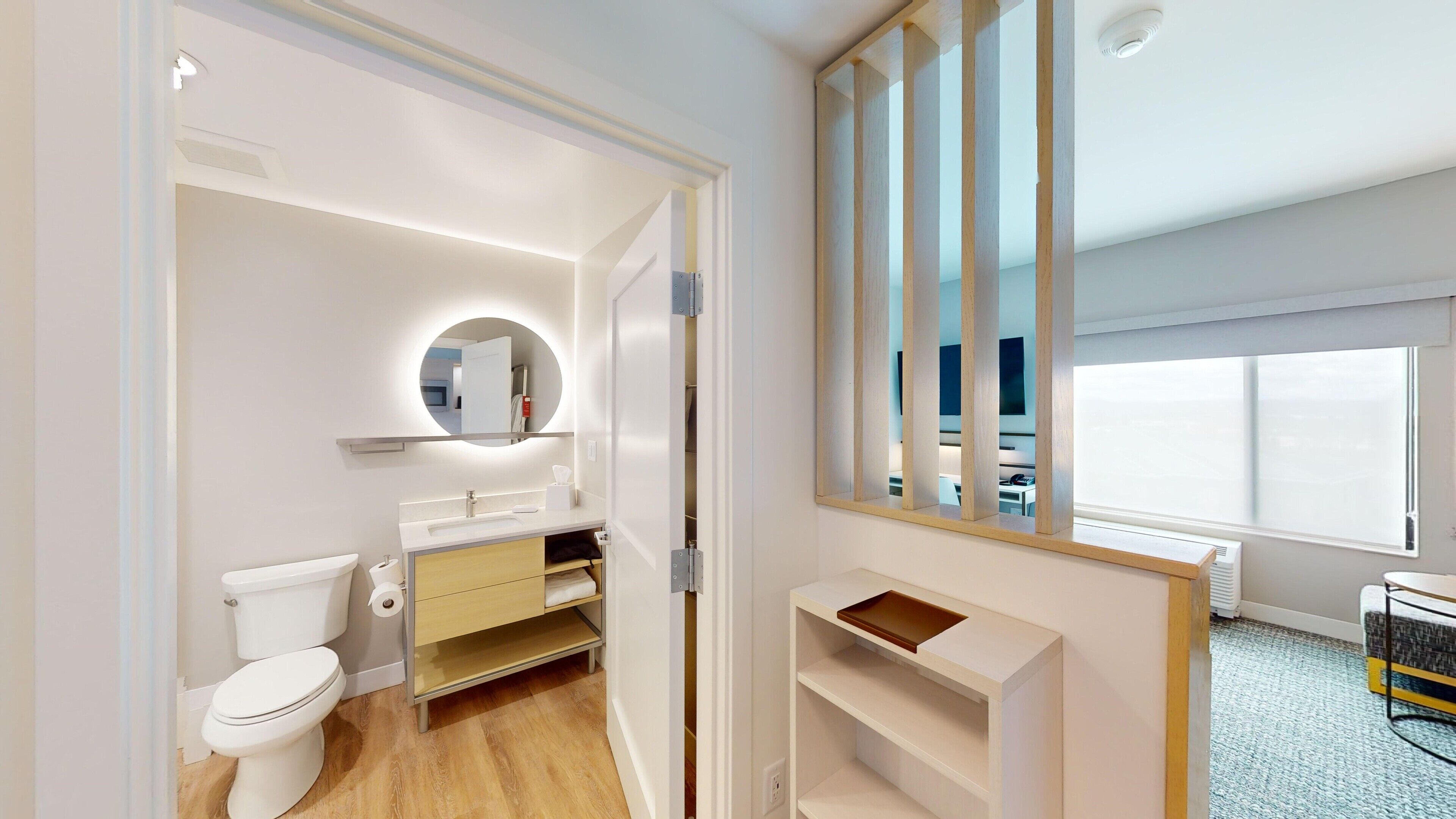 Un baño moderno con inodoro, lavamanos y espejo.