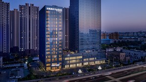A high-rise hotel with a modern glass facade, multiple floors, and illuminated signage. - Fairfield By Marriott Zibo (Zibo)