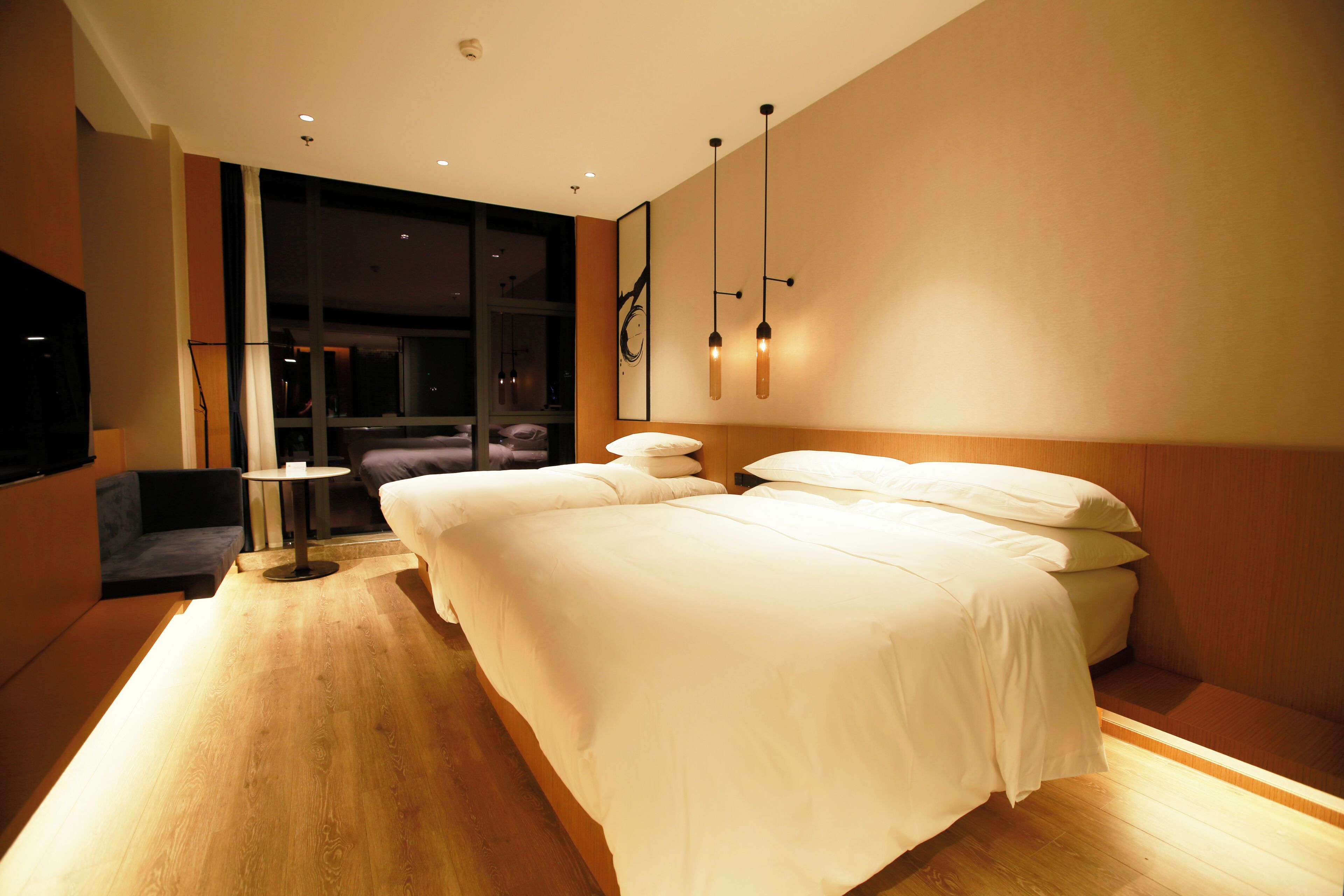 A modern hotel room with a large bed, a small round table, and a sofa.