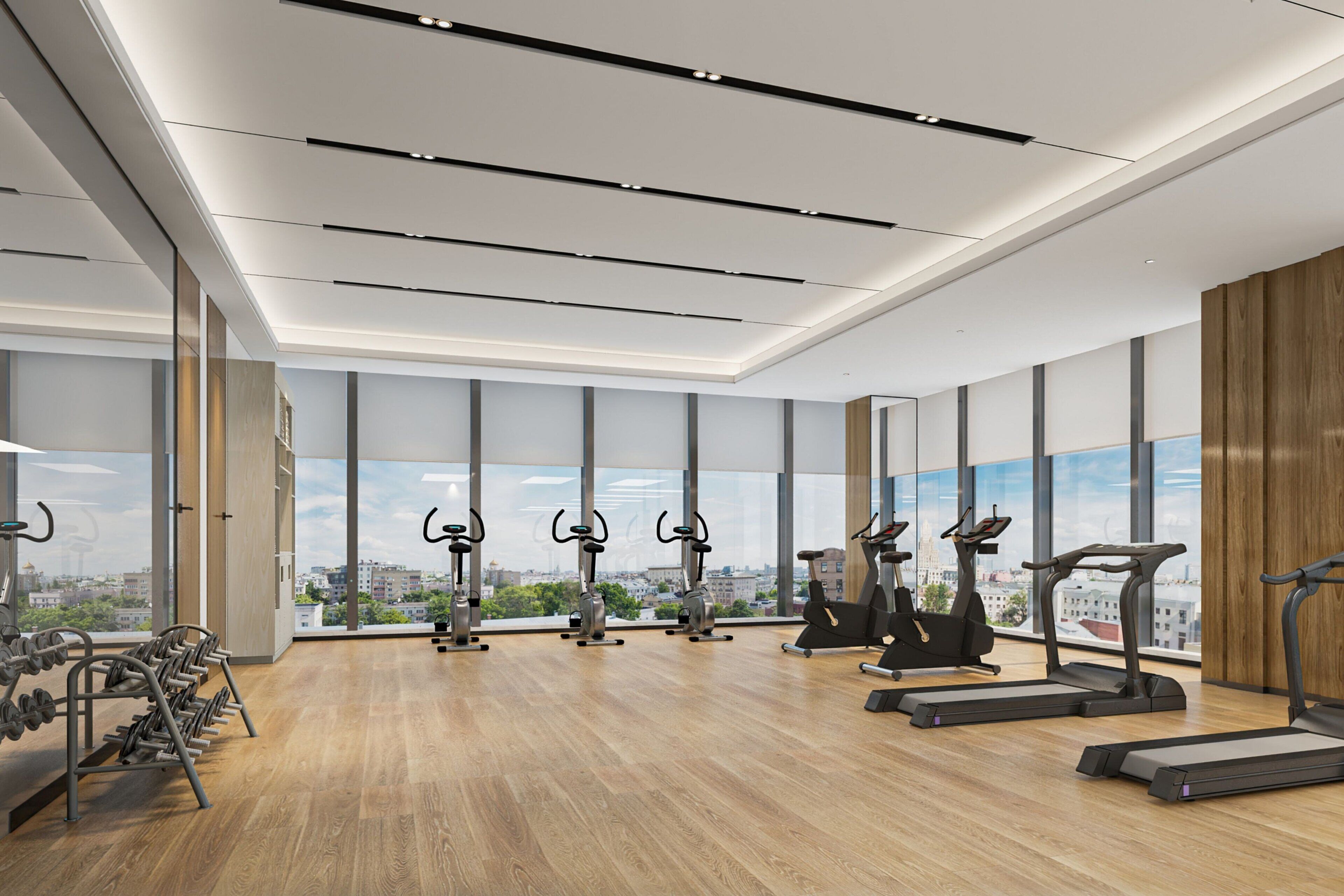 A modern gym with cardio equipment, large windows, and a city view.