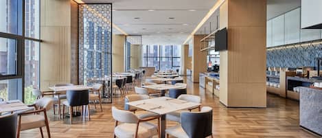 A modern dining area with wooden flooring, tables, and chairs.