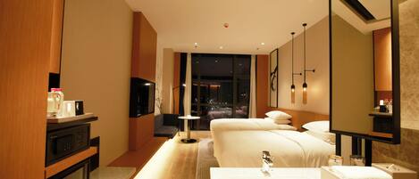 A hotel room with a large bed, a bedside table, a TV, a microwave, and a bathroom with a sink and mirror.