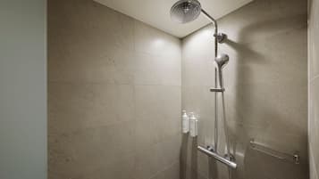 A shower with a handheld showerhead, a handheld showerhead, and a handheld showerhead.