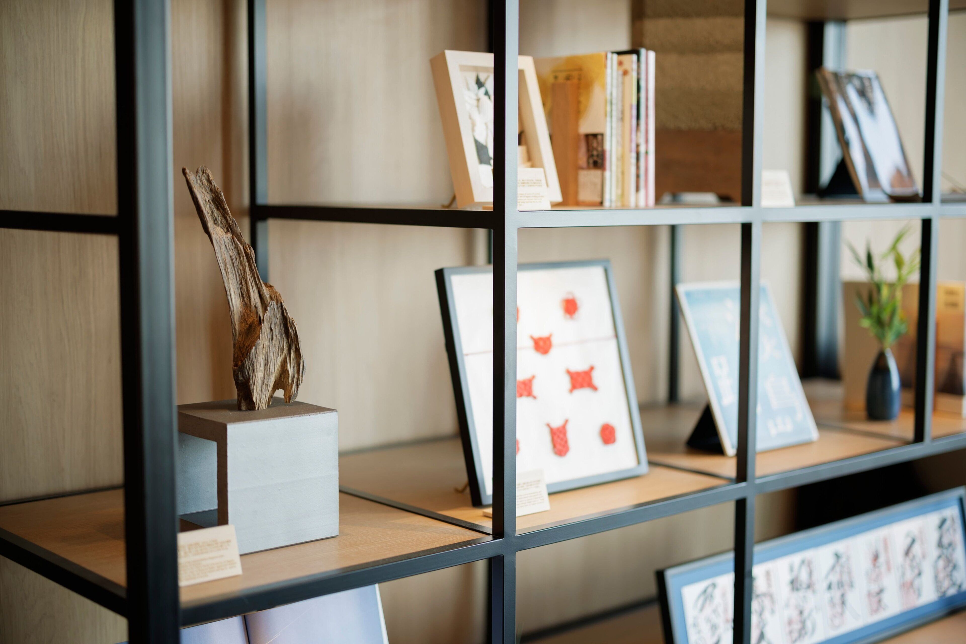 A bookshelf with various framed artworks and books.