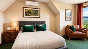 A bedroom with a bed, a nightstand, a chair, and two framed pictures on the wall.