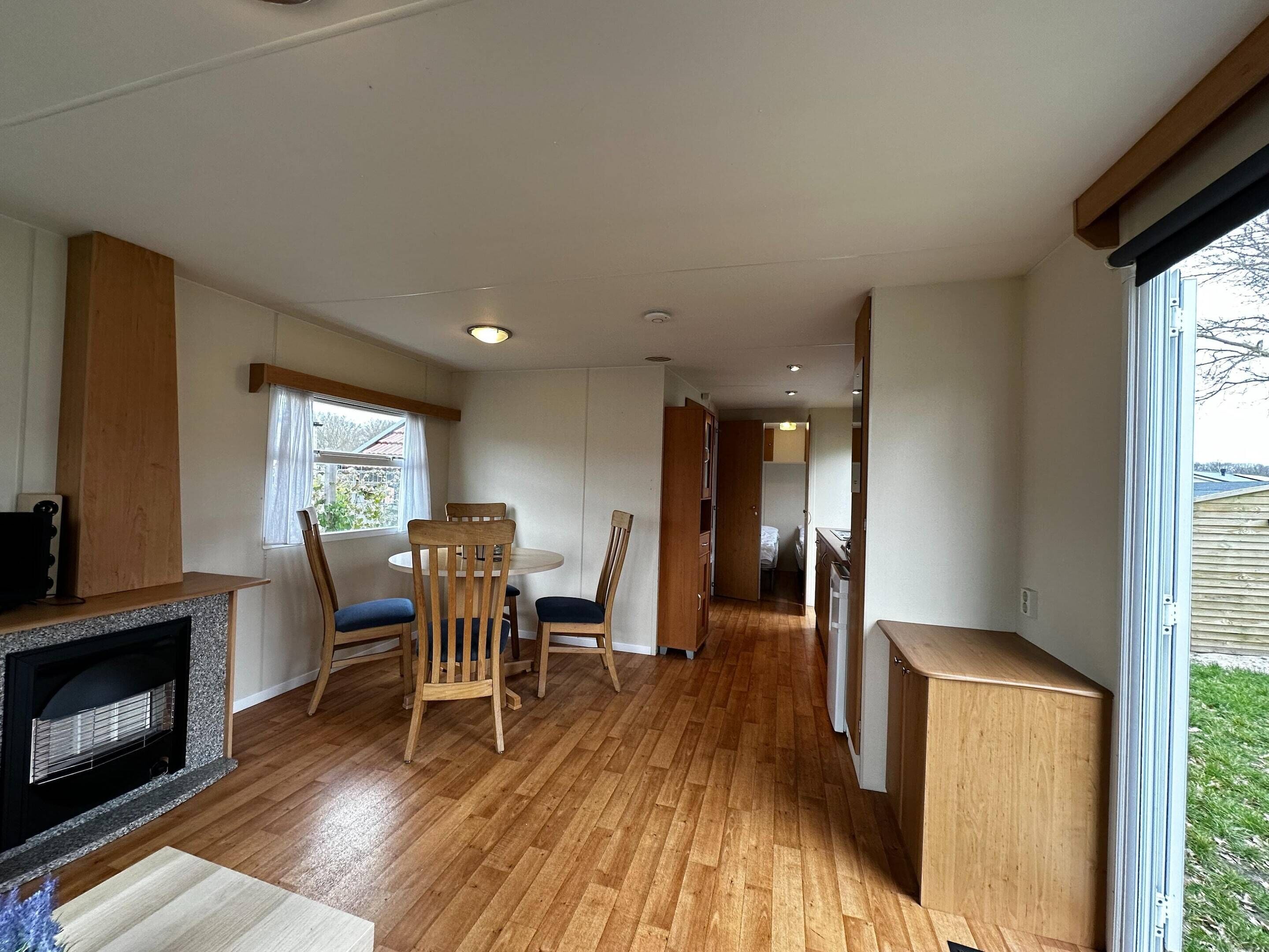 Ein kompakter Wohnraum mit Essbereich, Küchenzeile und Blick durch ein großes Fenster.