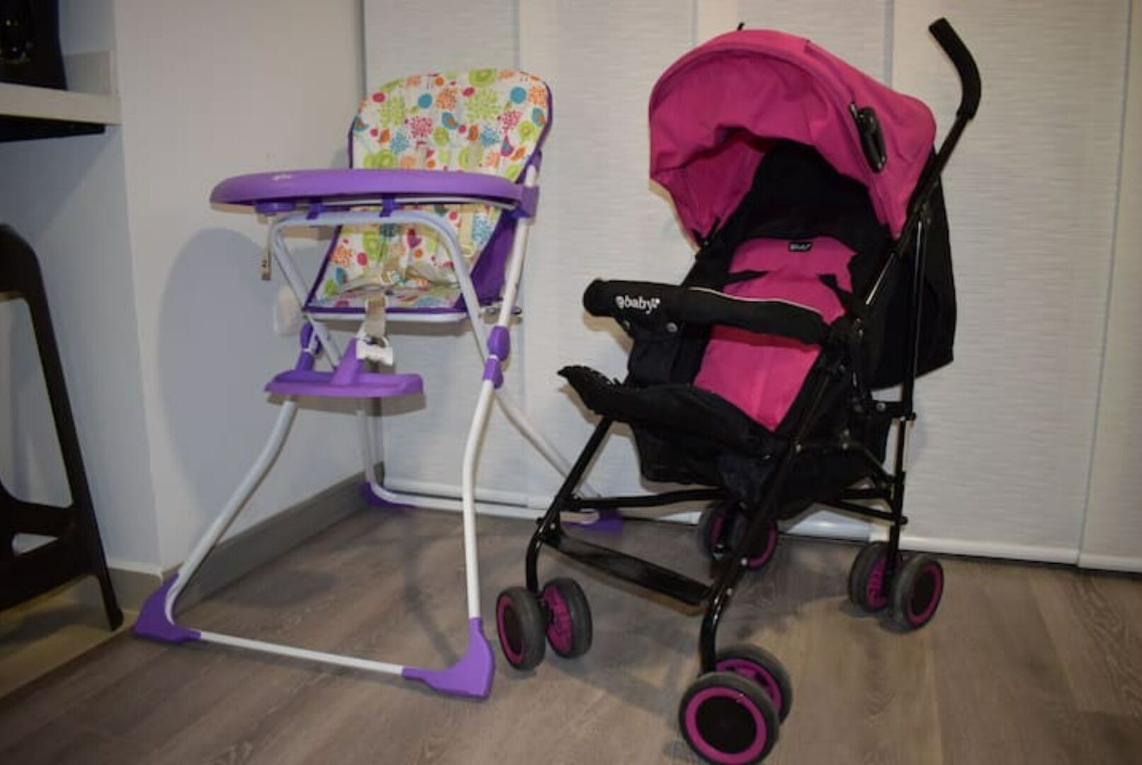 Ein Wickeltisch mit einer violetten Ablage und ein Kinderwagen mit einem rosa Verdeck.