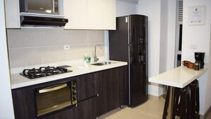 A modern kitchen with a gas stove, oven, microwave, sink, and black refrigerator. - Apartamento Familiar de Lujo al Lado del Lago (Paipa)
