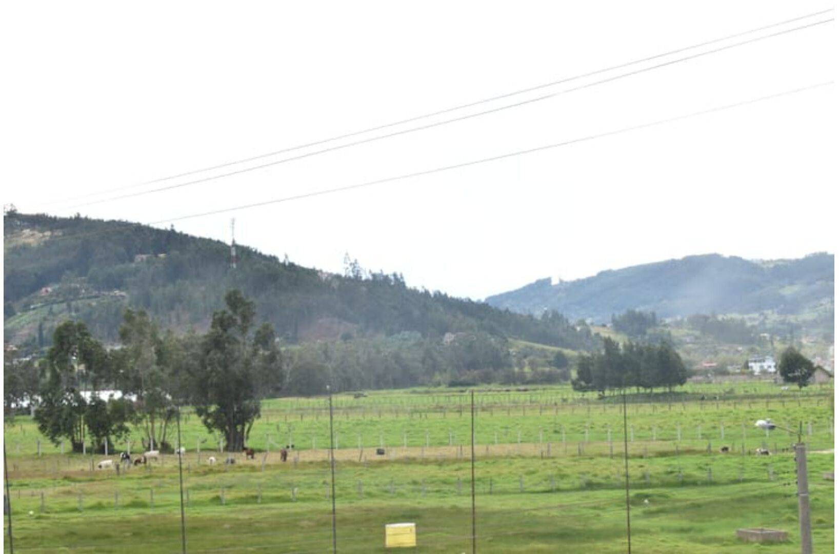 A rural landscape with fields, trees, and hills in the background.