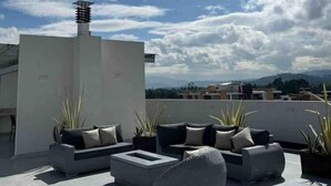 A rooftop terrace with outdoor seating, a chimney, and a view of the cityscape. - Apartamento Familiar de Lujo al Lado del Lago (Paipa)
