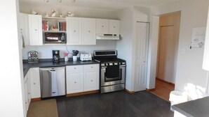 Une cuisine de taille réduite avec des meubles blancs, un lave-vaisselle, une cuisinière et un four à micro-ondes.