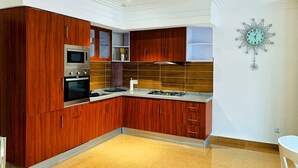 Une cuisine moderne avec des meubles en bois, des appareils électroménagers en acier inoxydable et une horloge murale décorative.
