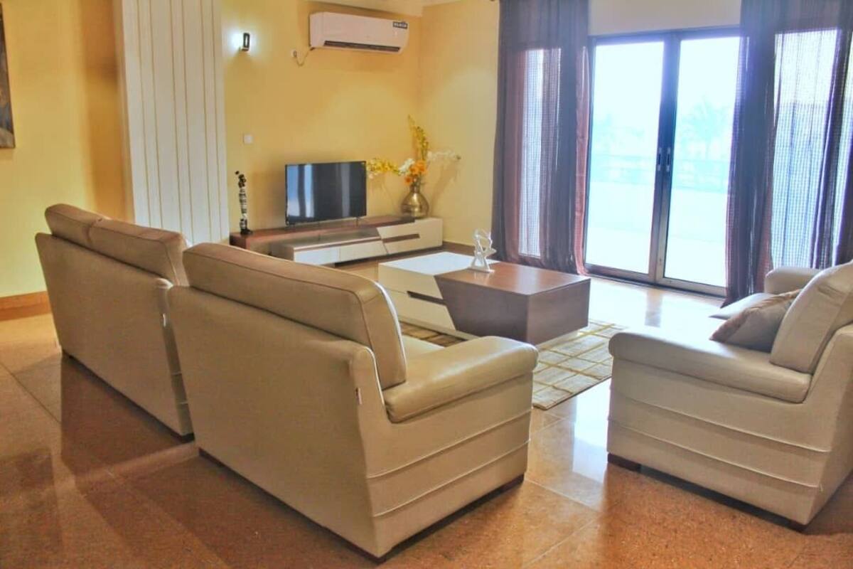 A living room with two beige sofas, a coffee table, and a flat-screen TV.