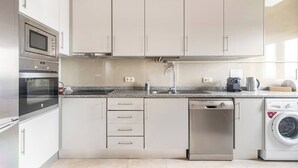 A modern kitchen with stainless steel appliances, a granite countertop, and white cabinetry.
