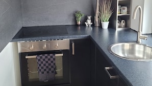 A modern kitchen with a built-in oven, a stainless steel sink, and a black countertop.