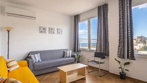 A living room with a grey sofa, a yellow armchair, a wooden coffee table, a black chair, and a potted plant. - Aegean Blue Apartment (Ligaria)