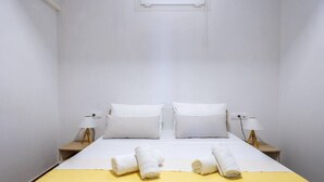 A hotel room with a bed, two bedside tables, a window, and a yellow bedspread. - Aegean Blue Apartment (Ligaria)