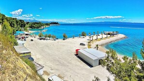 Zona costera con estacionamiento, un pequeño edificio y playa.