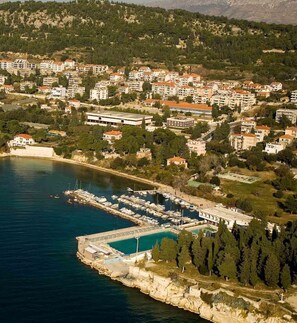Stunning coastal town with a marina, surrounded by lush greenery and rolling hills.