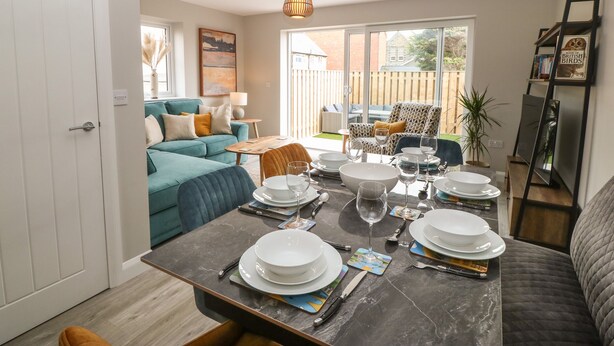 A dining area with a table set for four, a sofa, and a view of the backyard.