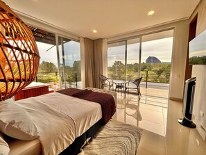 Un dormitorio moderno con una cama grande, un balcón con vistas al paisaje y un televisor.