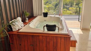 Une salle de bain avec une baignoire en bois, un banc et une vue sur un paysage montagneux.
