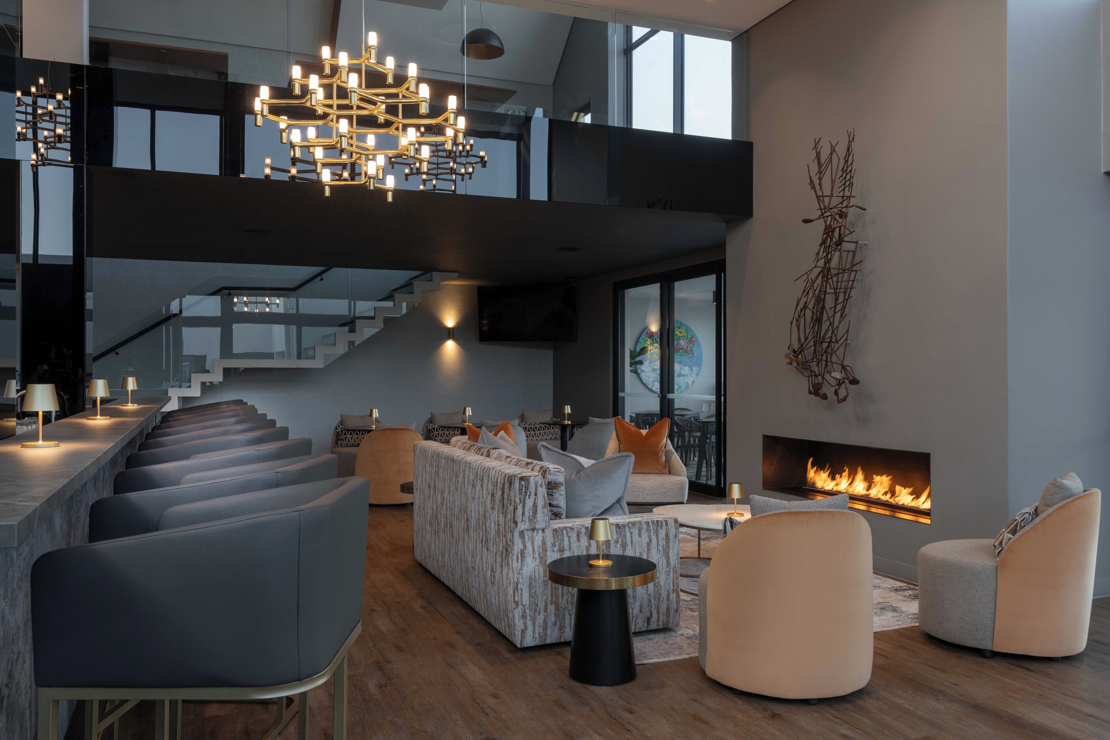 Una sala de estar moderna con chimenea, zona de estar y una escalera que conduce a un nivel superior.