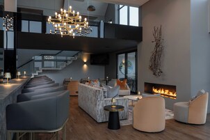 Una sala de estar moderna con chimenea, zona de estar y una escalera que conduce a un nivel superior.