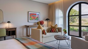 A modern hotel room with a sofa, armchair, and a small table. There is a large window with a view of the outdoors. - The Hazendal Hotel and Spa (Stellenbosch)
