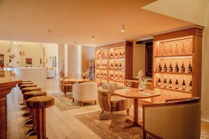 Un hall de hotel con zona de bar, asientos y exhibición de vinos.