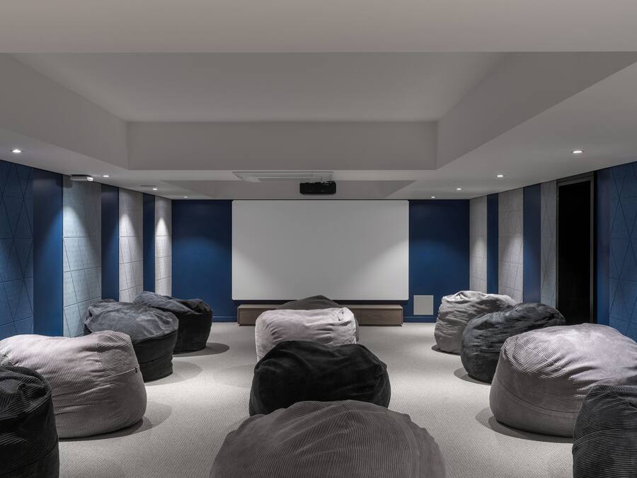 A modern conference room with a large screen, multiple seating areas, and a neutral color scheme.
