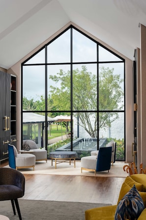 A spacious living room with a large window, a fireplace, and a view of a garden. - The Hazendal Hotel and Spa (Stellenbosch)