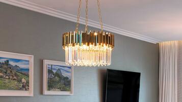 A dining room with a chandelier, a television mounted on the wall, and a table set for four.