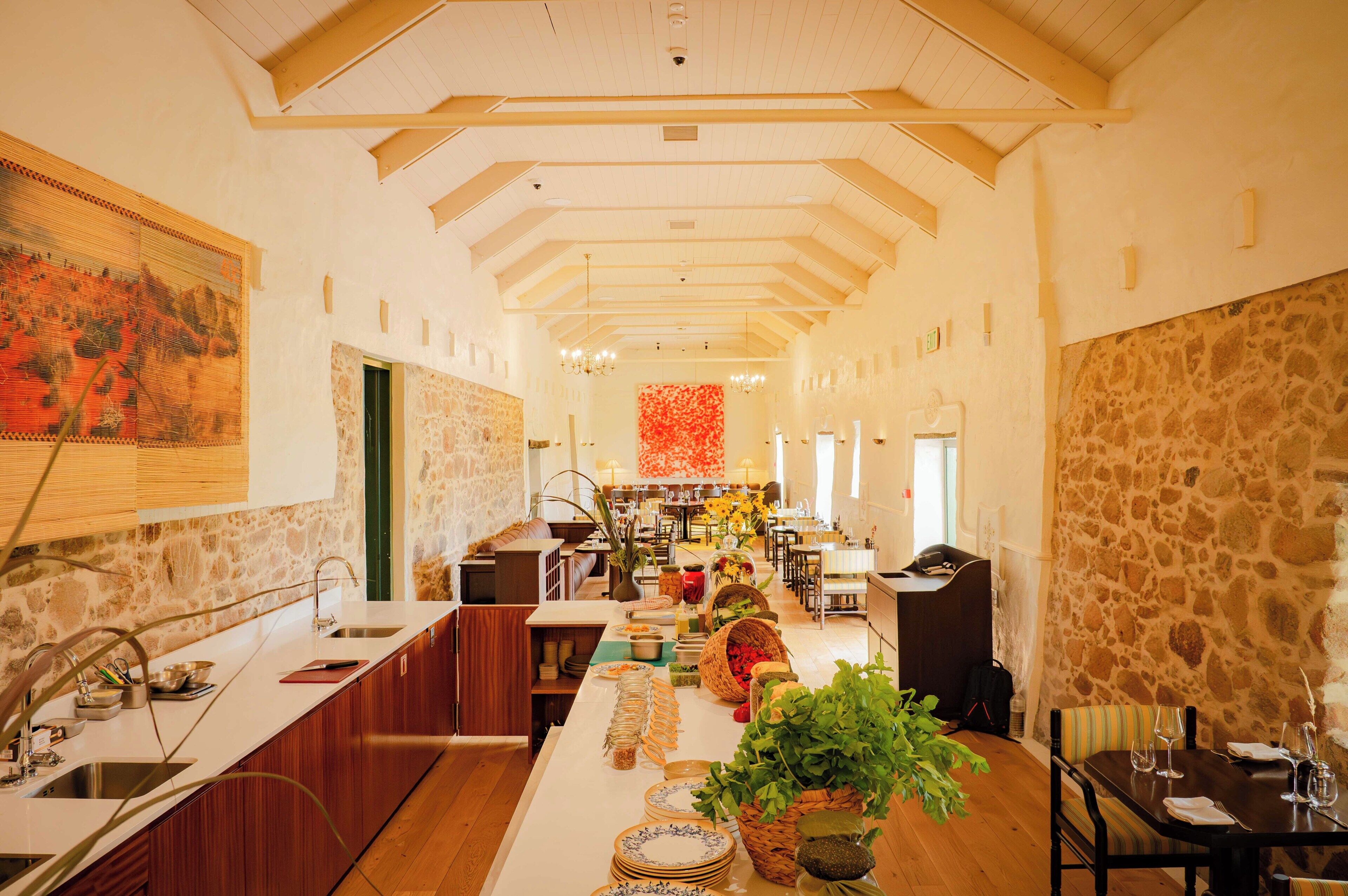 A spacious kitchen with a long island, stone walls, and a high ceiling with wooden beams.