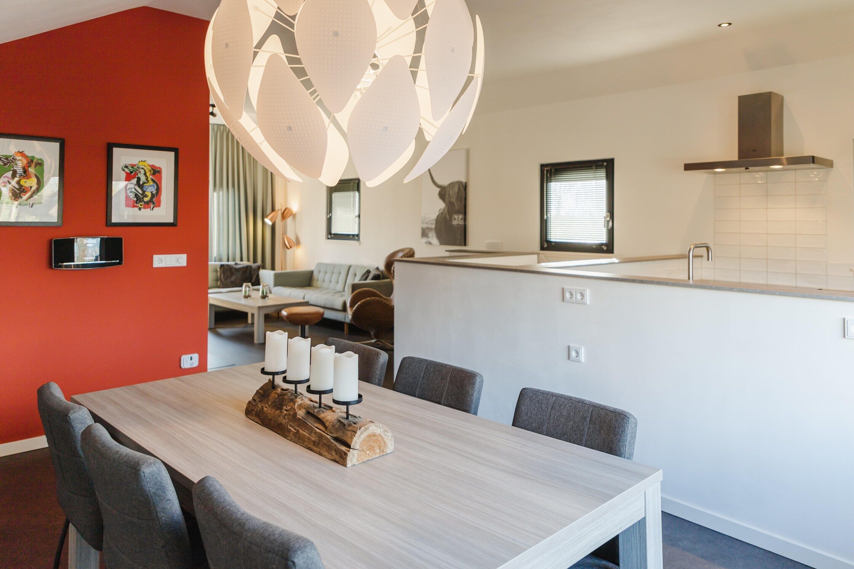 A modern kitchen with a central island, a dining area with a wooden table and chairs, and a living space with a sofa and a coffee table.