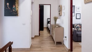 A hallway with wooden flooring, a wooden staircase, a cream-colored dresser, and a framed certificate on the wall.