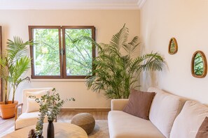 A living room with a sofa, a coffee table, and potted plants.