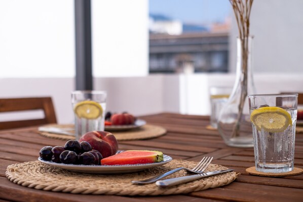 A wooden table with a plate of fruit, a glass of water, and a vase.
