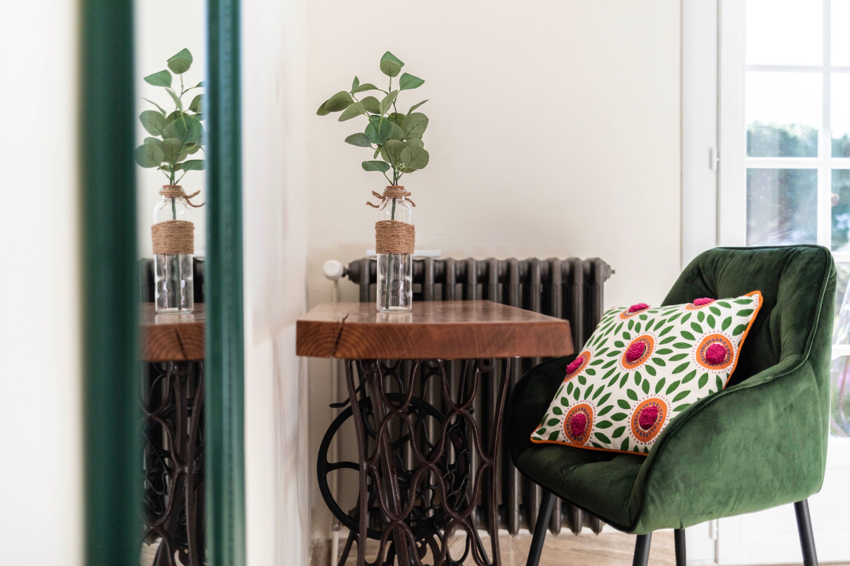 A room with a green armchair, a small table with a plant, and a radiator.