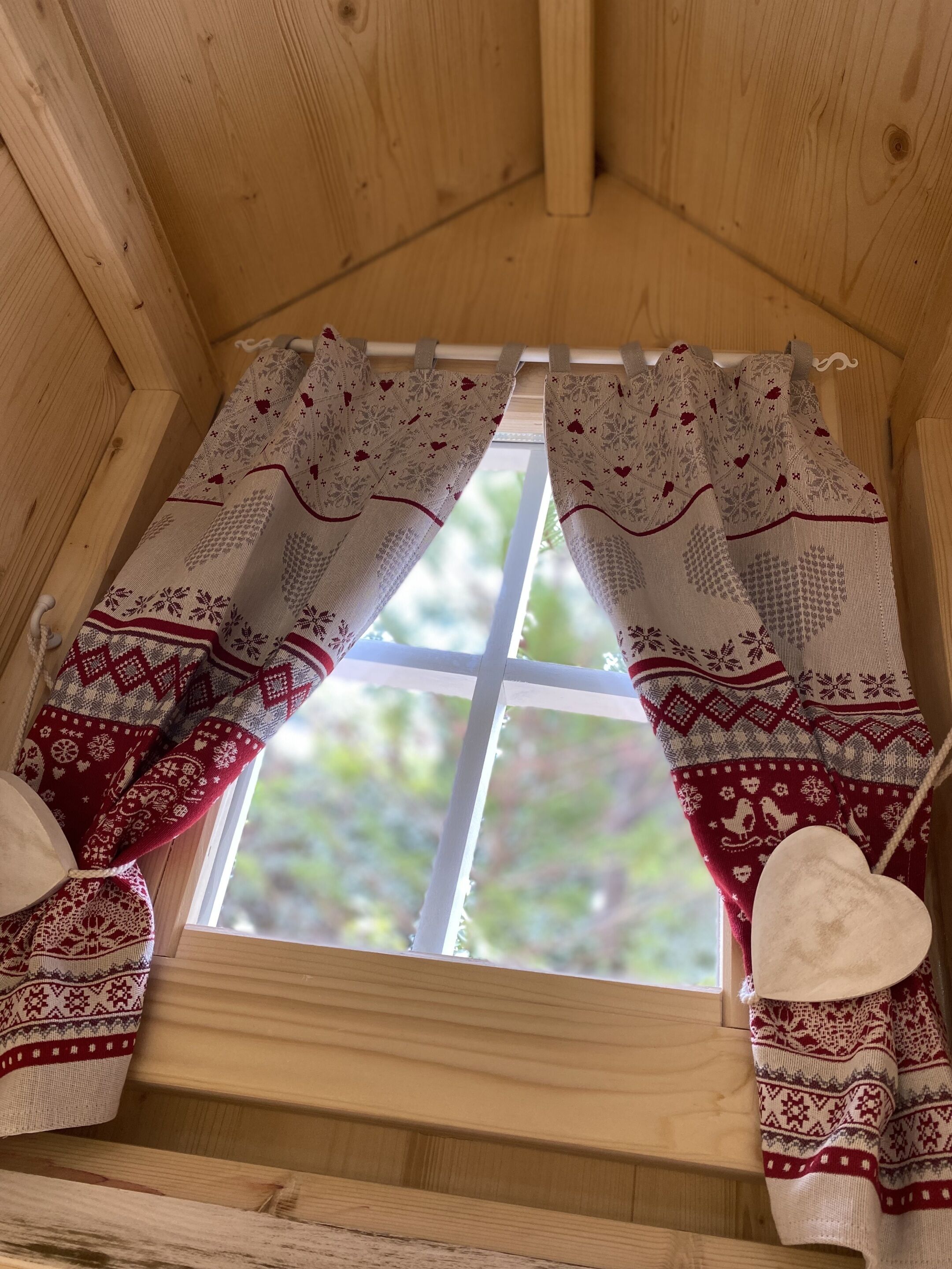 A window with wooden shutters and patterned curtains.