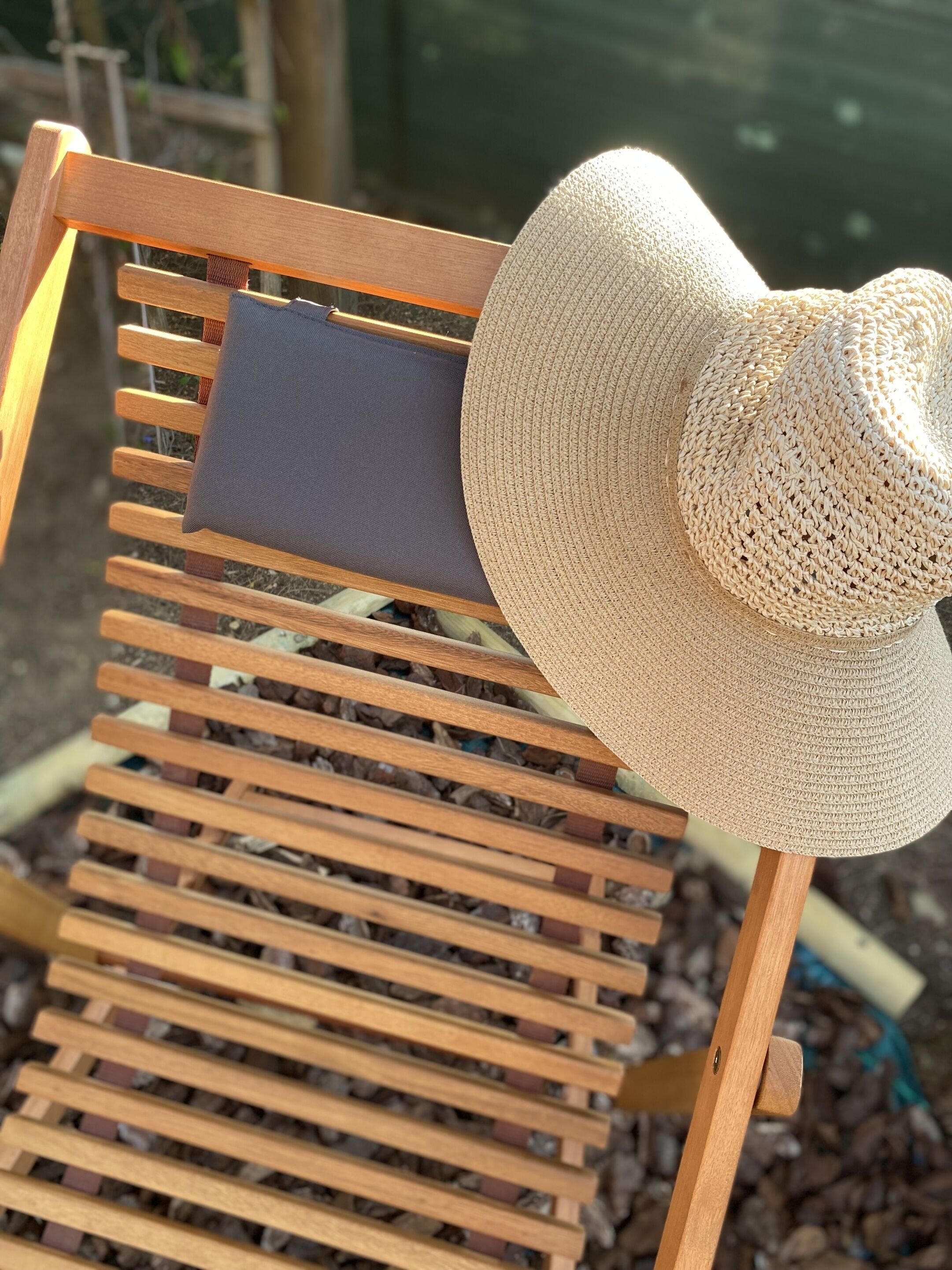 A wooden chair with a woven hat placed on it.