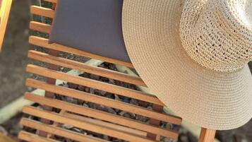 A wooden chair with a woven hat placed on it.