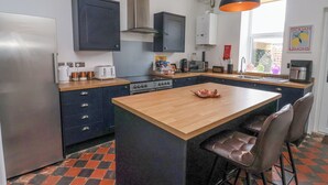 A modern kitchen with a central island, dark cabinets, and a checkered floor pattern. - The Old Station House (Withernsea)