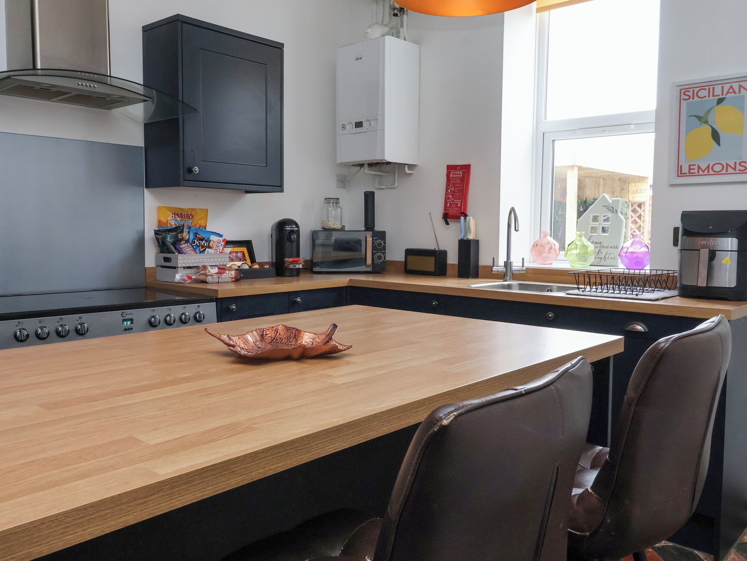 A modern kitchen with a central island, a built-in oven, and a microwave.