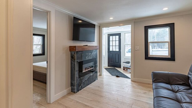 A modern living room with a fireplace, a mounted TV, and a leather couch. - Cozy Cabin in a Rural Setting #16 near Temple,NH (Temple)