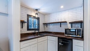 A compact kitchen with white cabinetry, a built-in microwave, and a dishwasher. - Cozy Cabin in a Rural Setting #16 near Temple,NH (Temple)