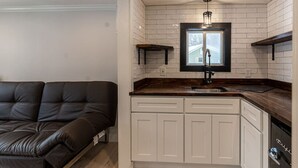 A compact kitchen with white cabinets, a black countertop, and a window above the sink. - Cozy Cabin in a Rural Setting #16 near Temple,NH (Temple)