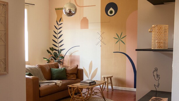 Ein Wohnzimmer mit einem braunen Ledersofa, einem kleinen runden Tisch, einem Teppich und einem Bücherregal mit einem dekorativen Gegenstand.