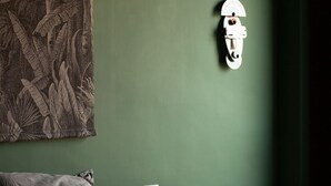 Ein Schlafzimmer mit einem Bett, Kissen, einem Nachttisch, einer Lampe und einer Wandleuchte.